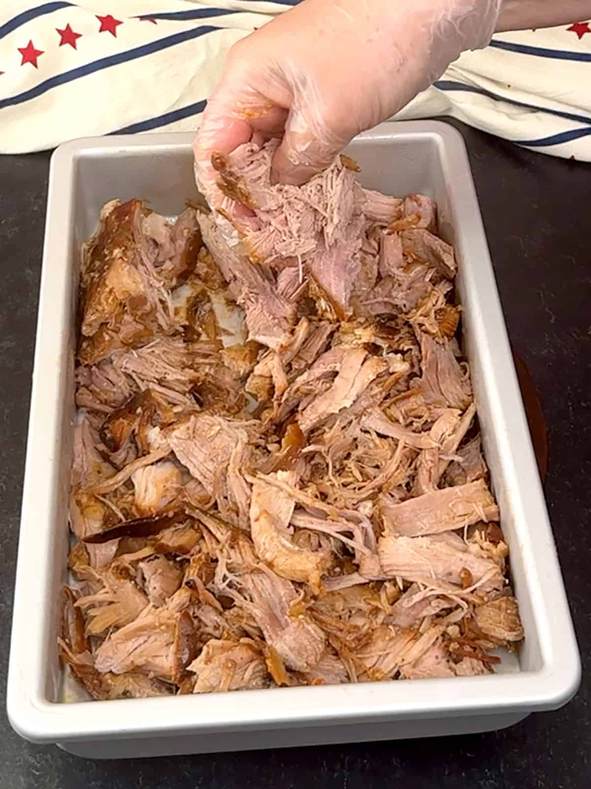 pulling pork with gloved hands