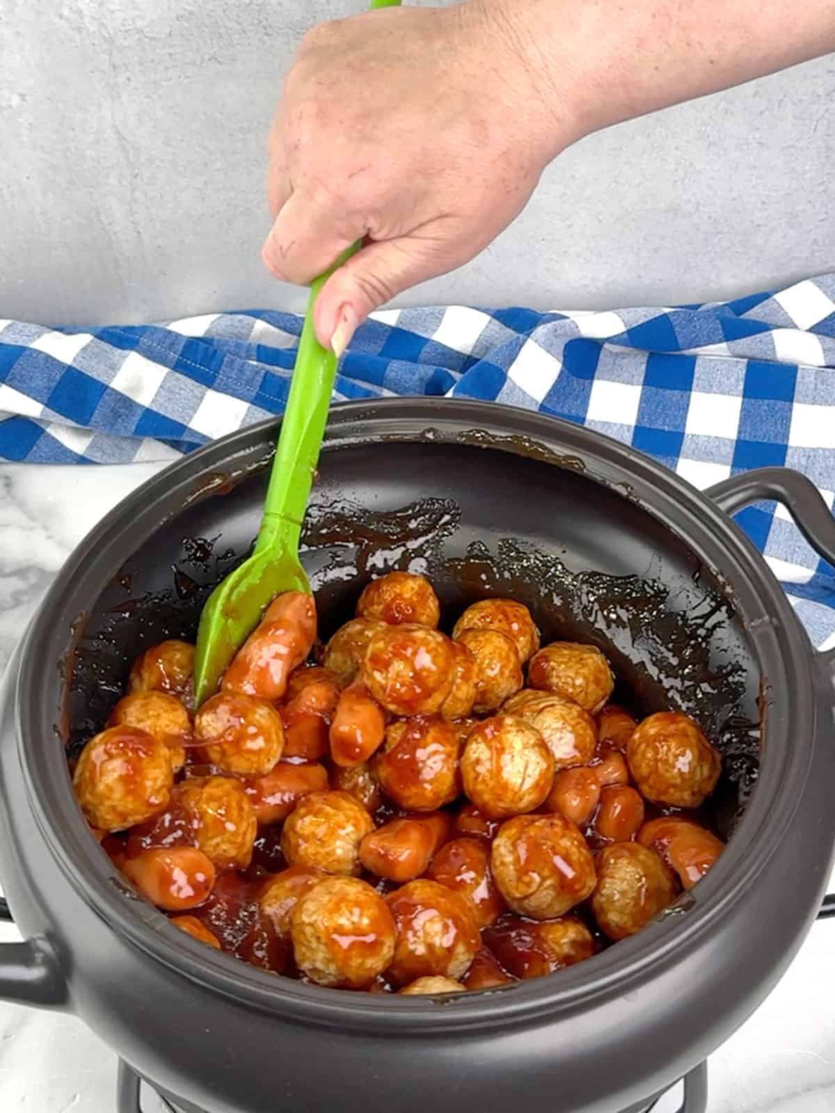 stirring smokies and meatballs into sauce