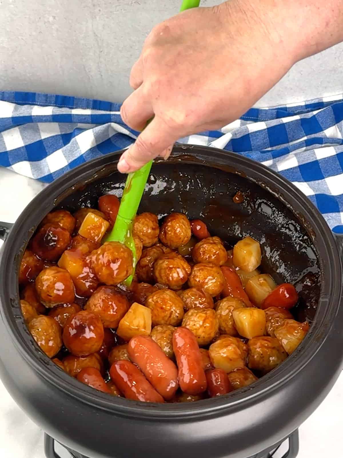stirring pineapple int meatballs and smokies
