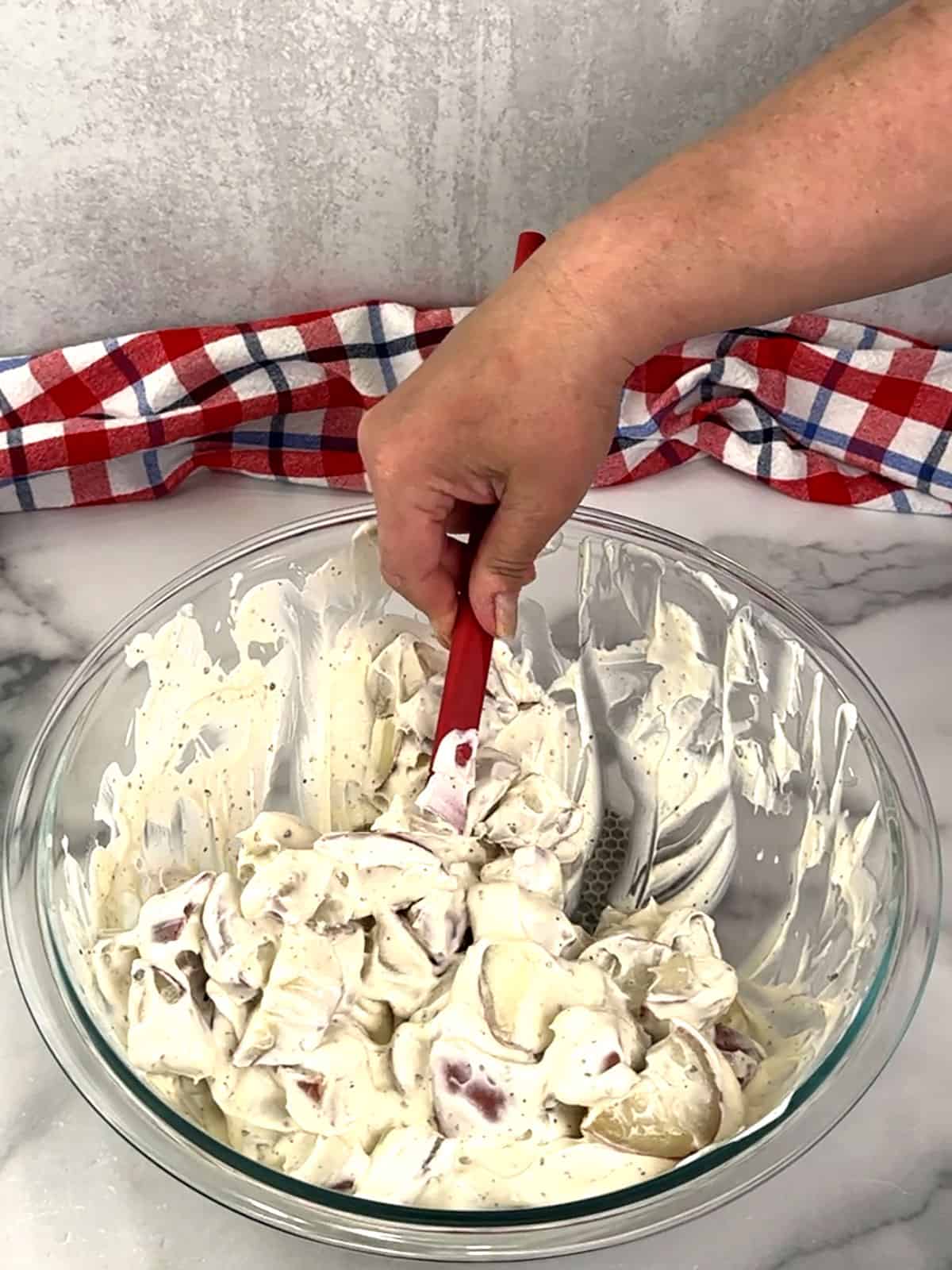 stirring potatoes with dressing