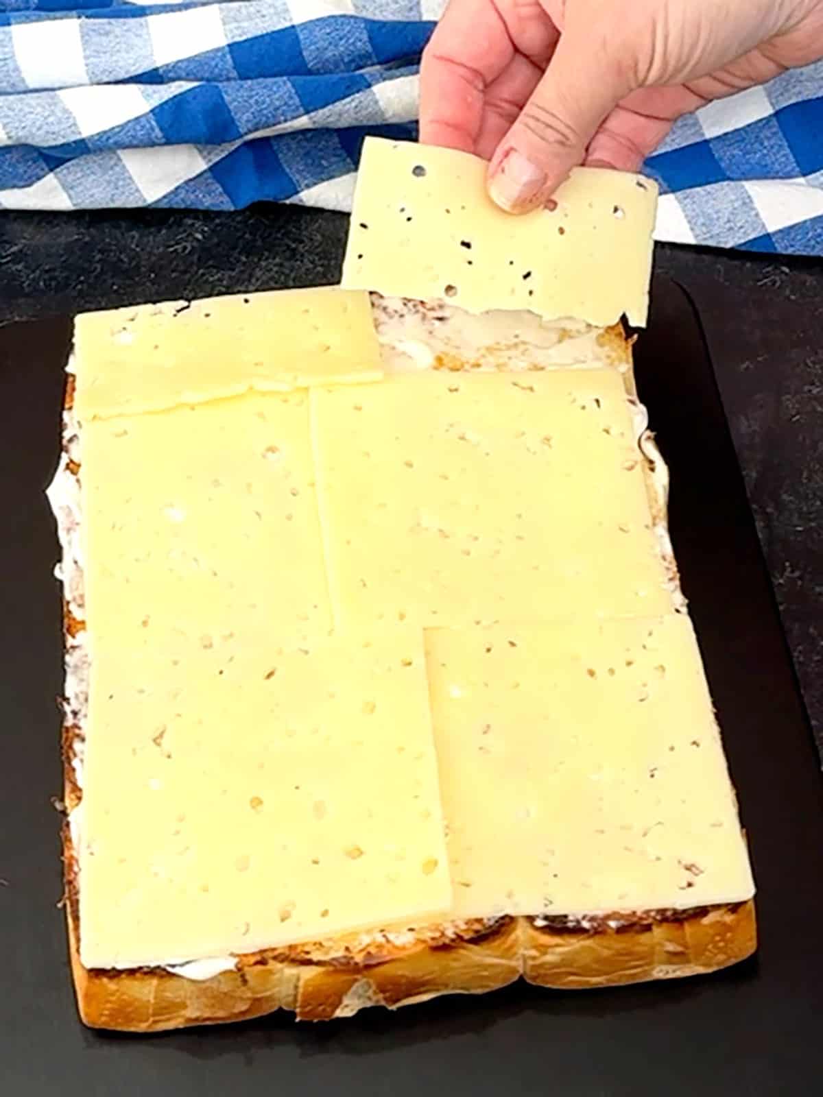 placing Swiss cheese on top of many on bottom buns