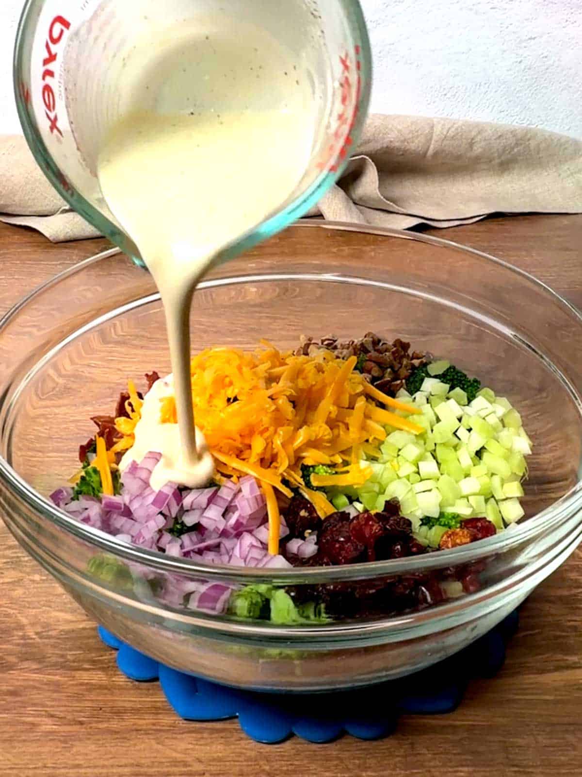 Adding the dressing to the broccoli salad.