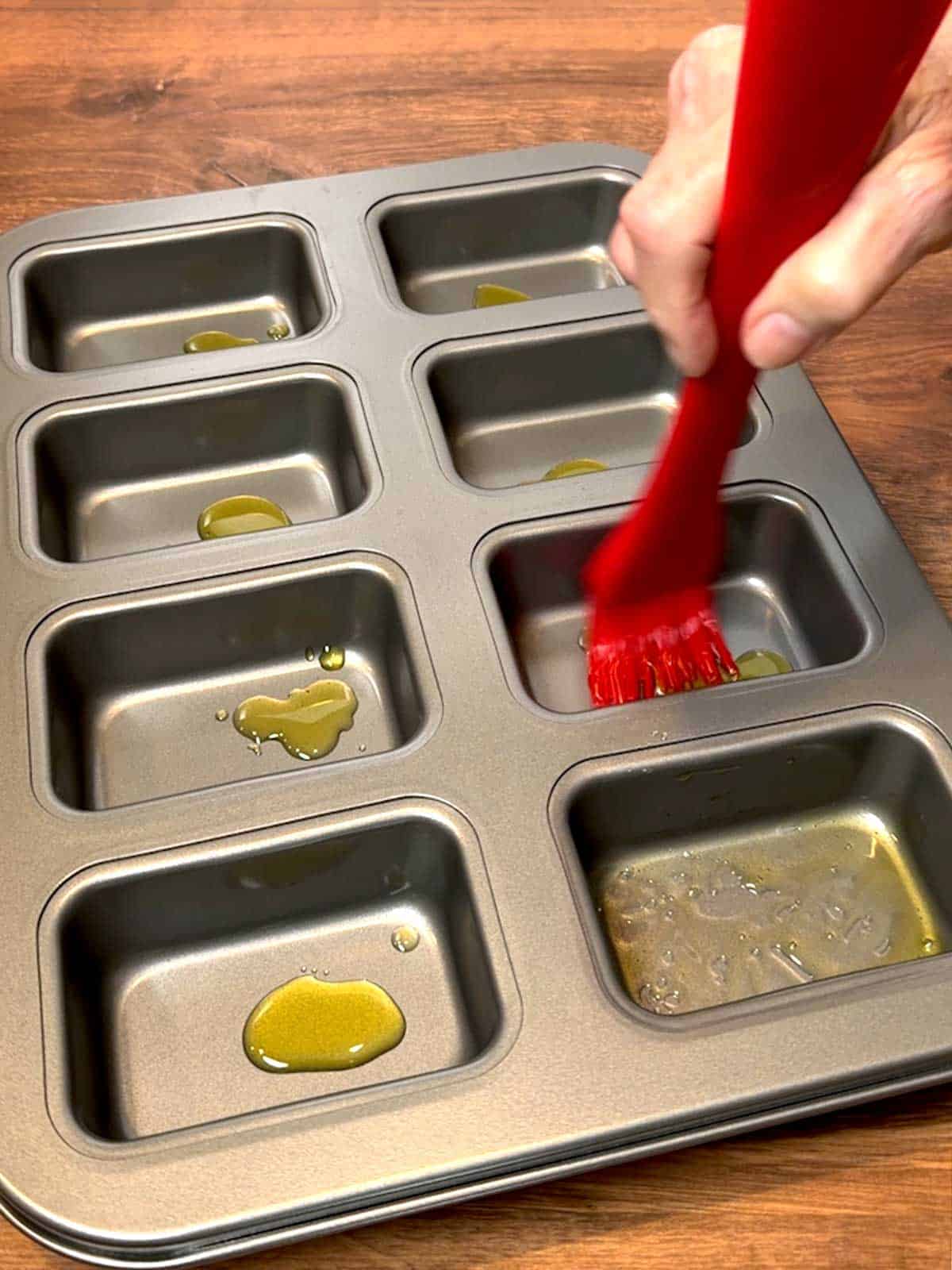 Brushing olive oil in each of the pan's cavities.
