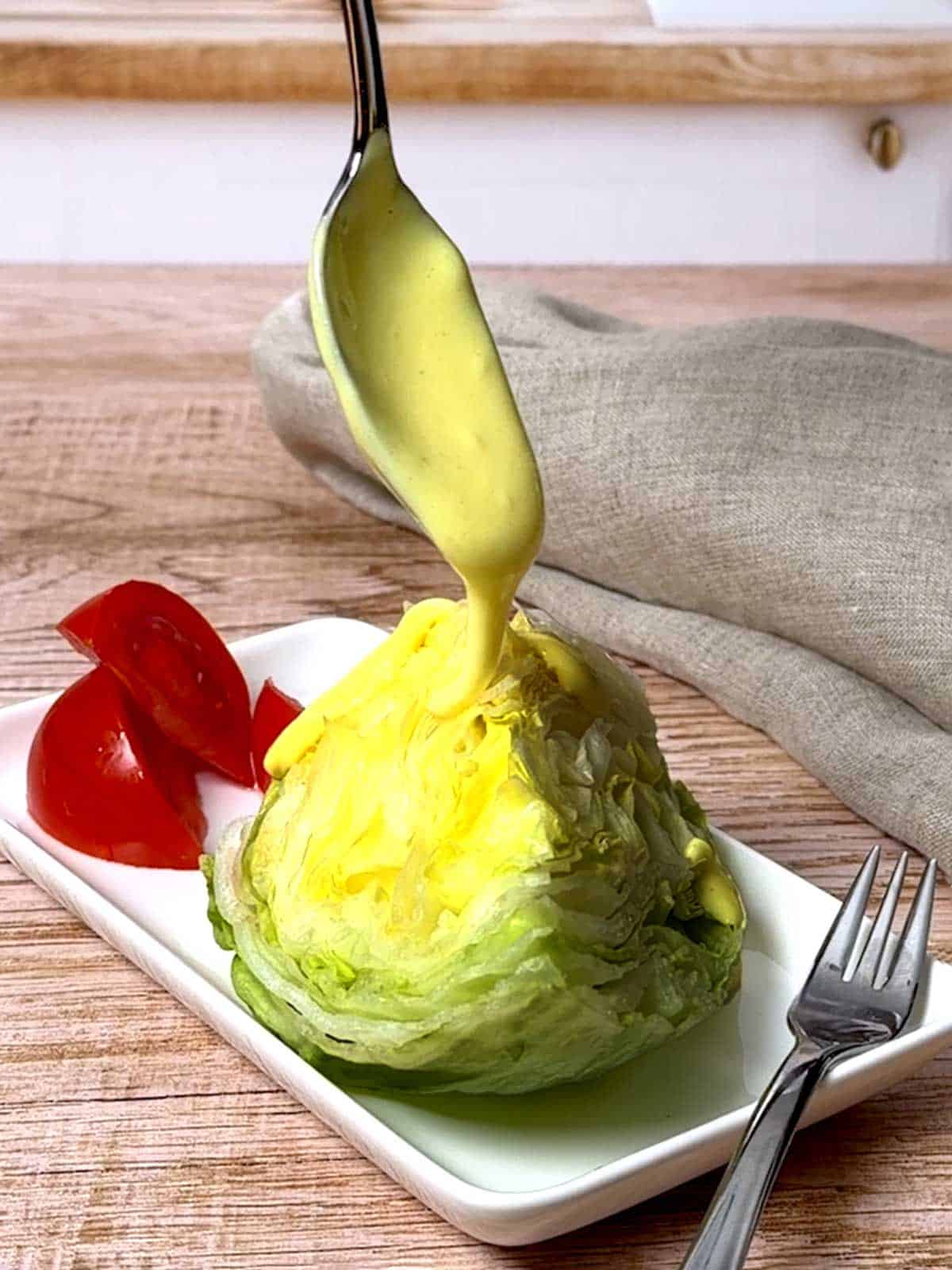 Spooning homemade salad cream on lettucer wedge.