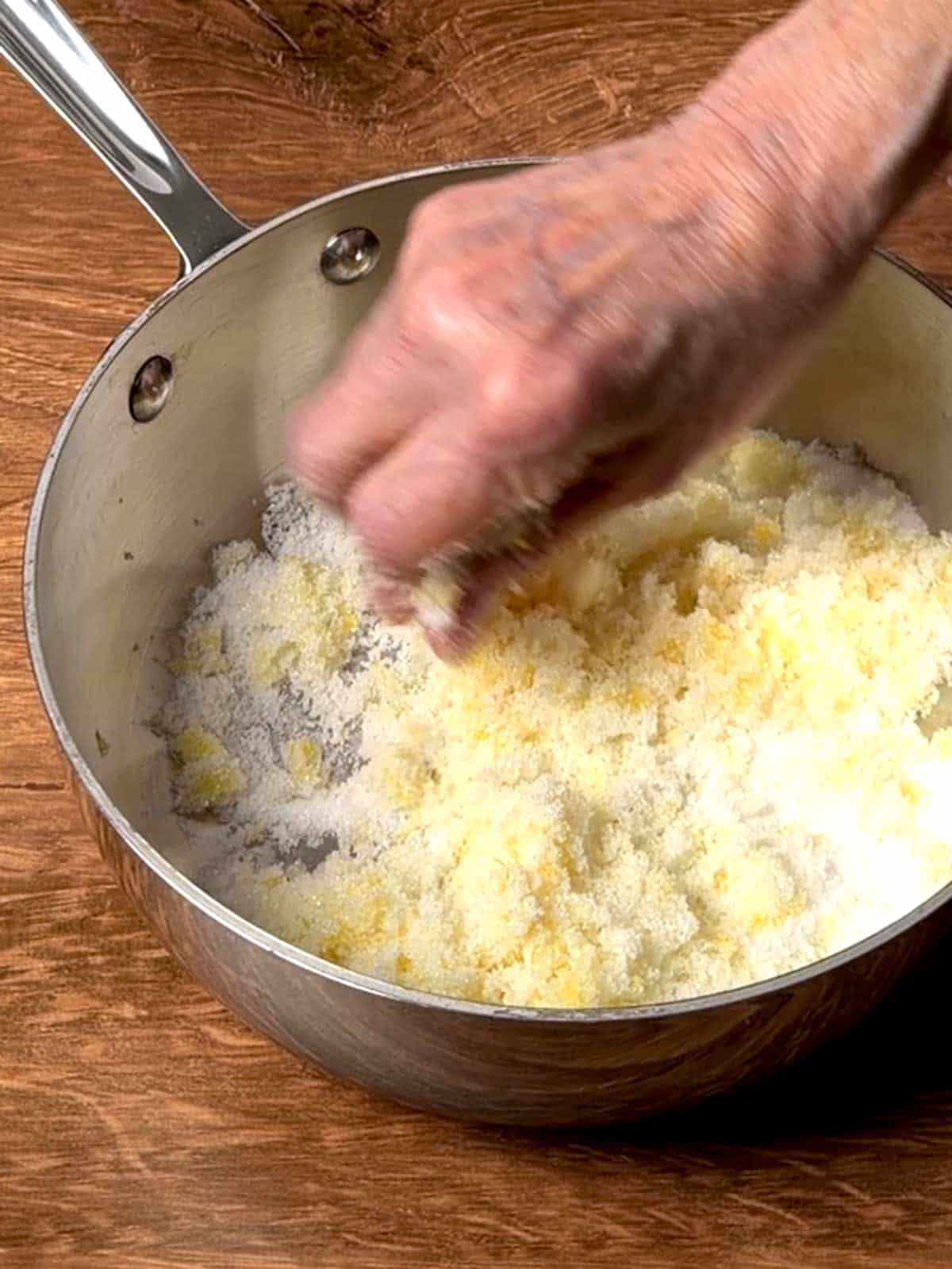 Rubbing lemon zest into granulated sugar.
