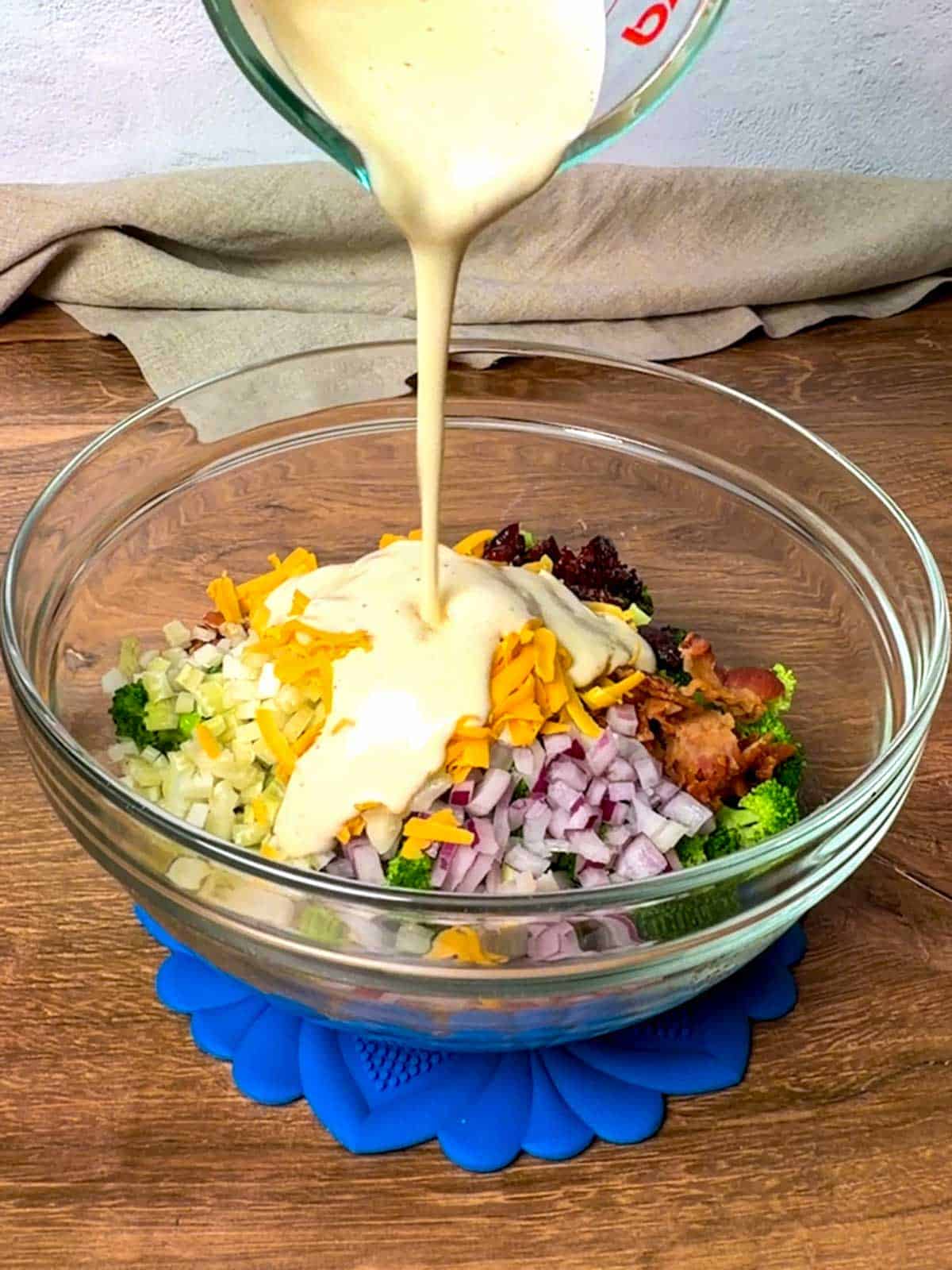 Pouring dressing on Broccoli Salad.