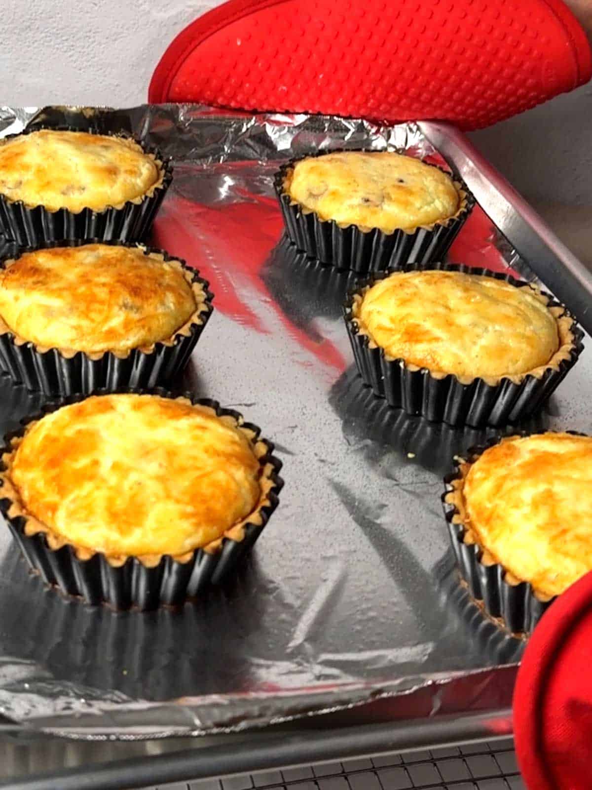 Removing the mini quiches from the oven.