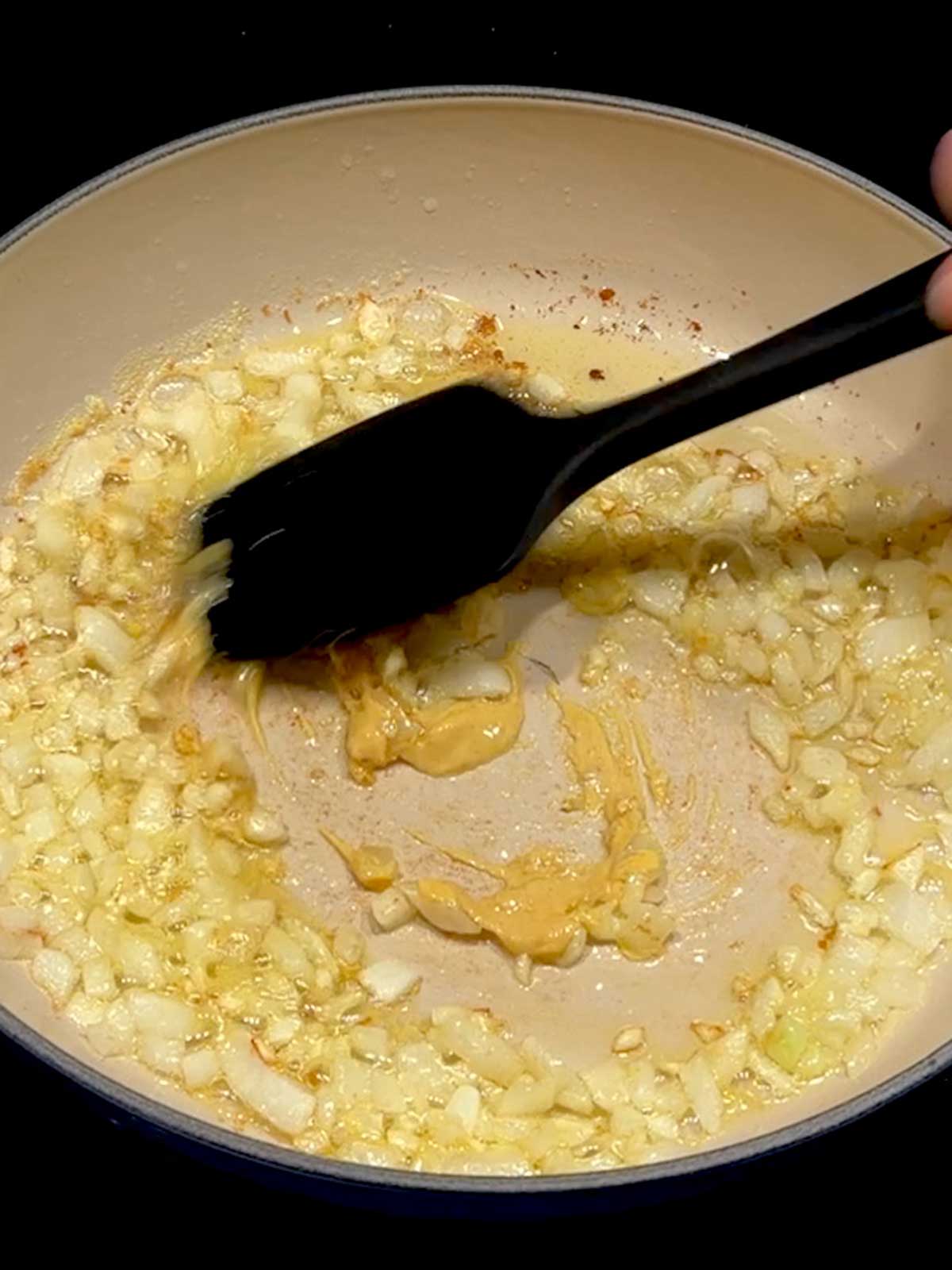 Stirring mustard into the onions and garlic in the braiser.