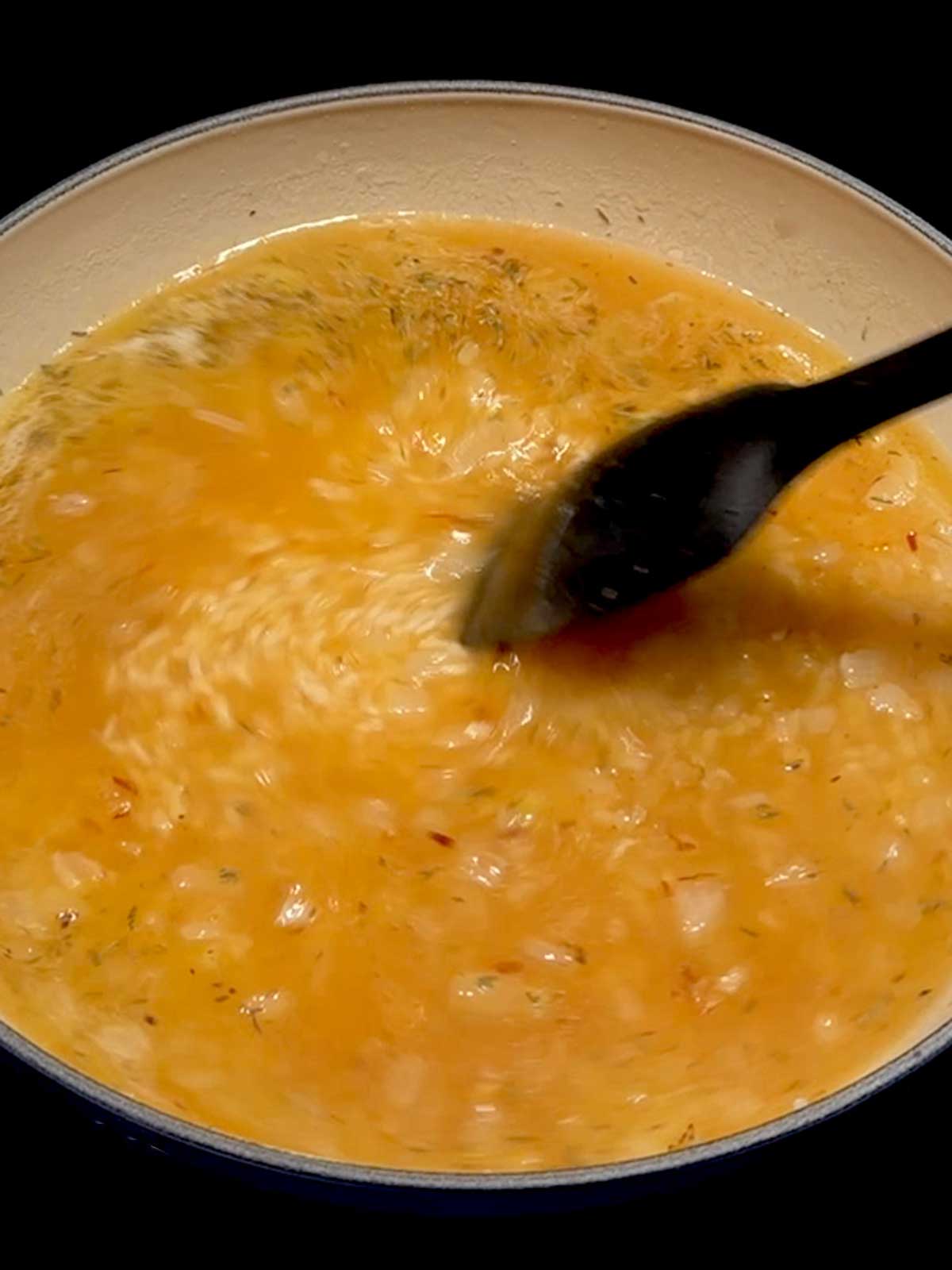 Stirring the rice with the chicken broth.