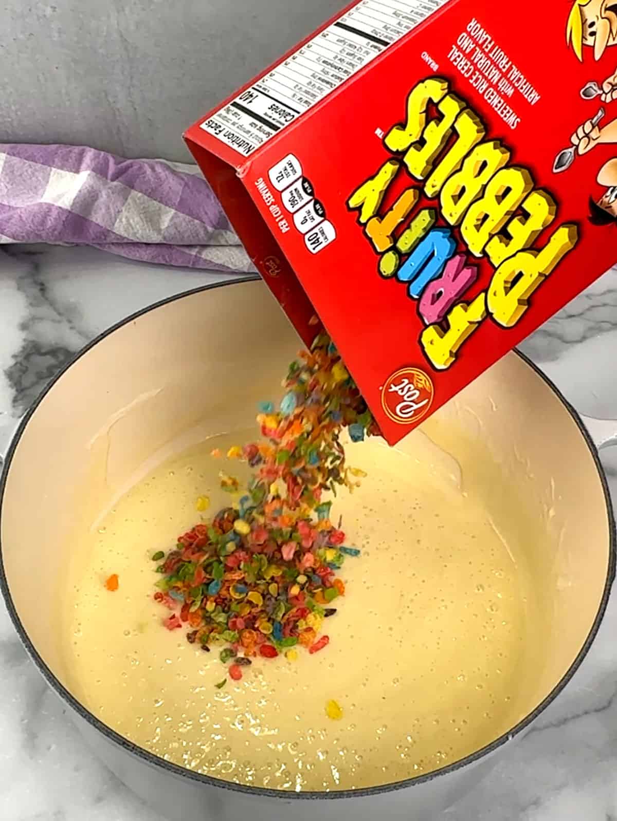 adding fruity pebbles to melted marshmallow mixture