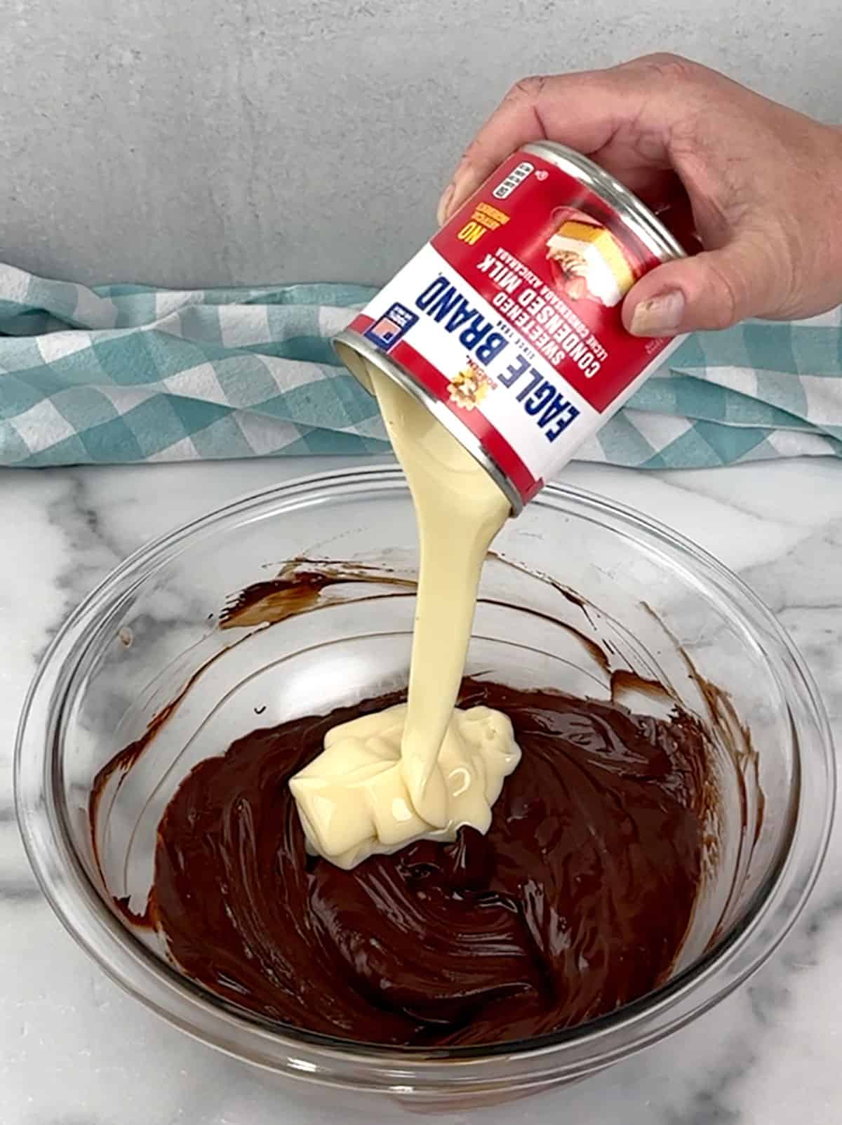 adding sweetened condensed milk to melted chocolate mixture