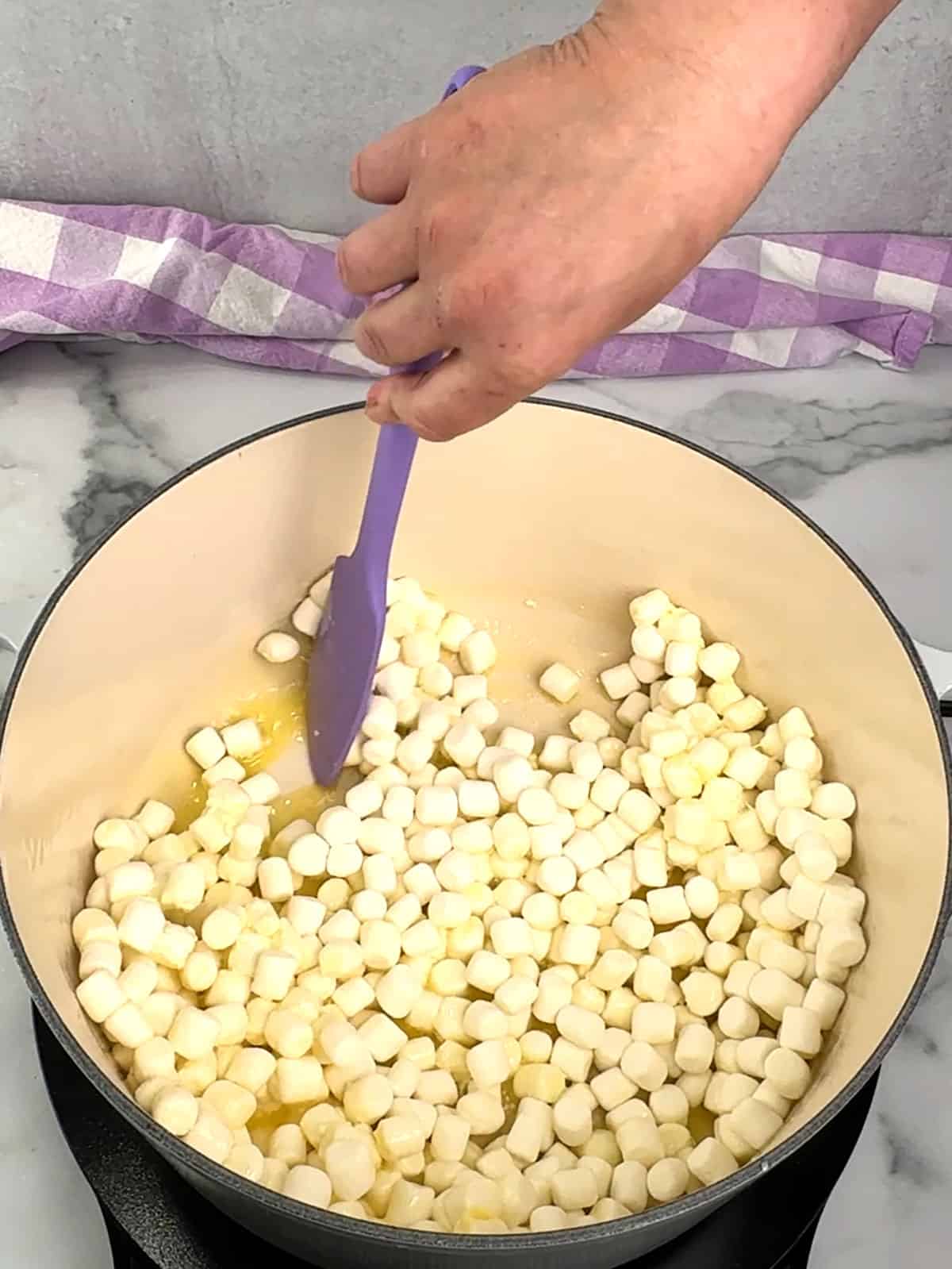 stirring marshmallows into melted butter