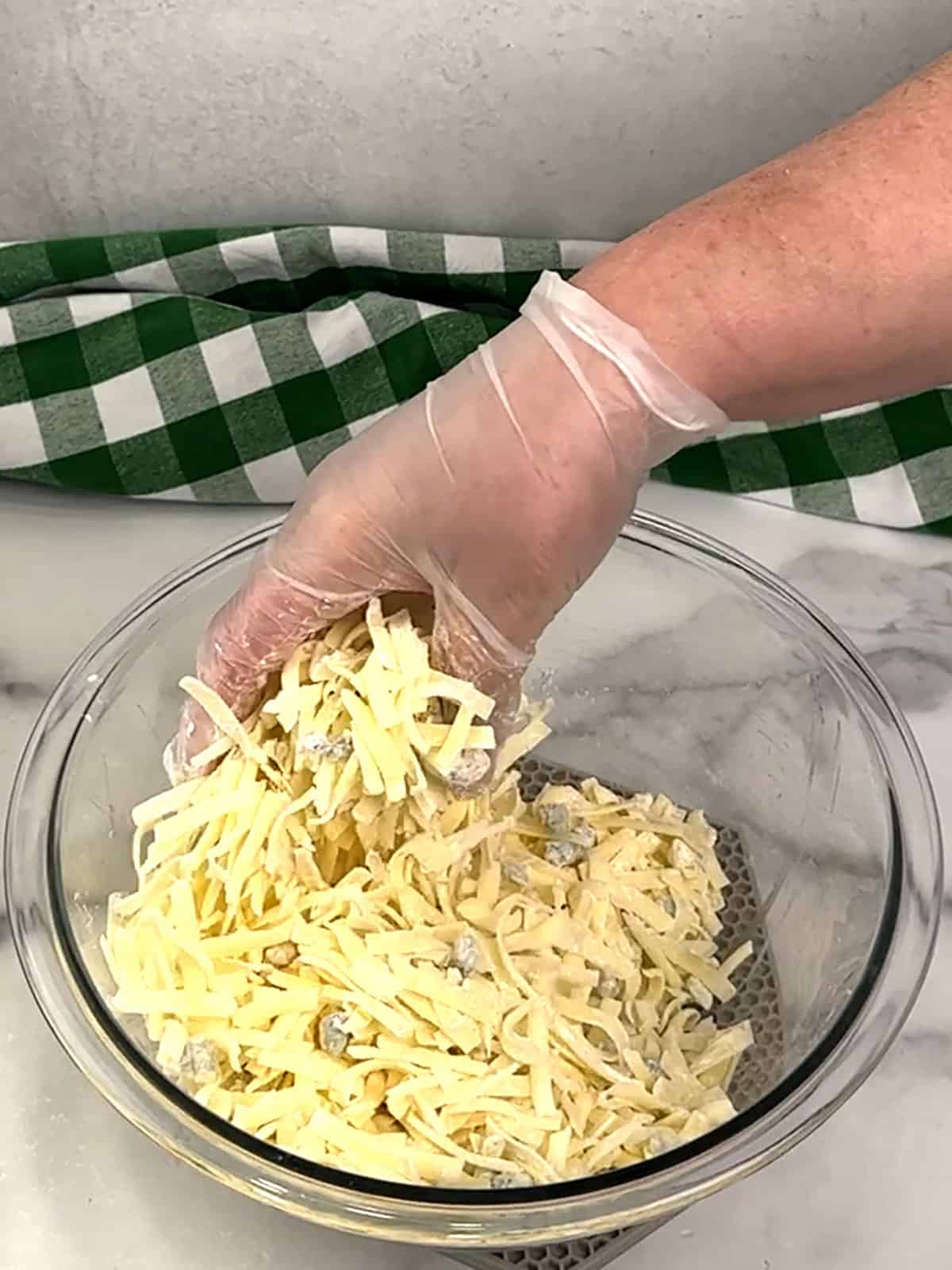 combining cheeses and cornstarch with gloved hands