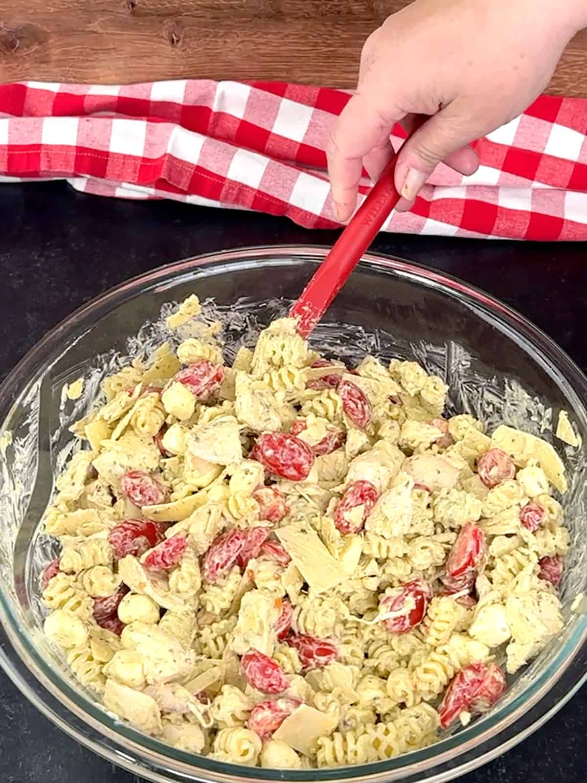 stirring Quick and Easy Pesto Chicken Caprese Pasta Salad together