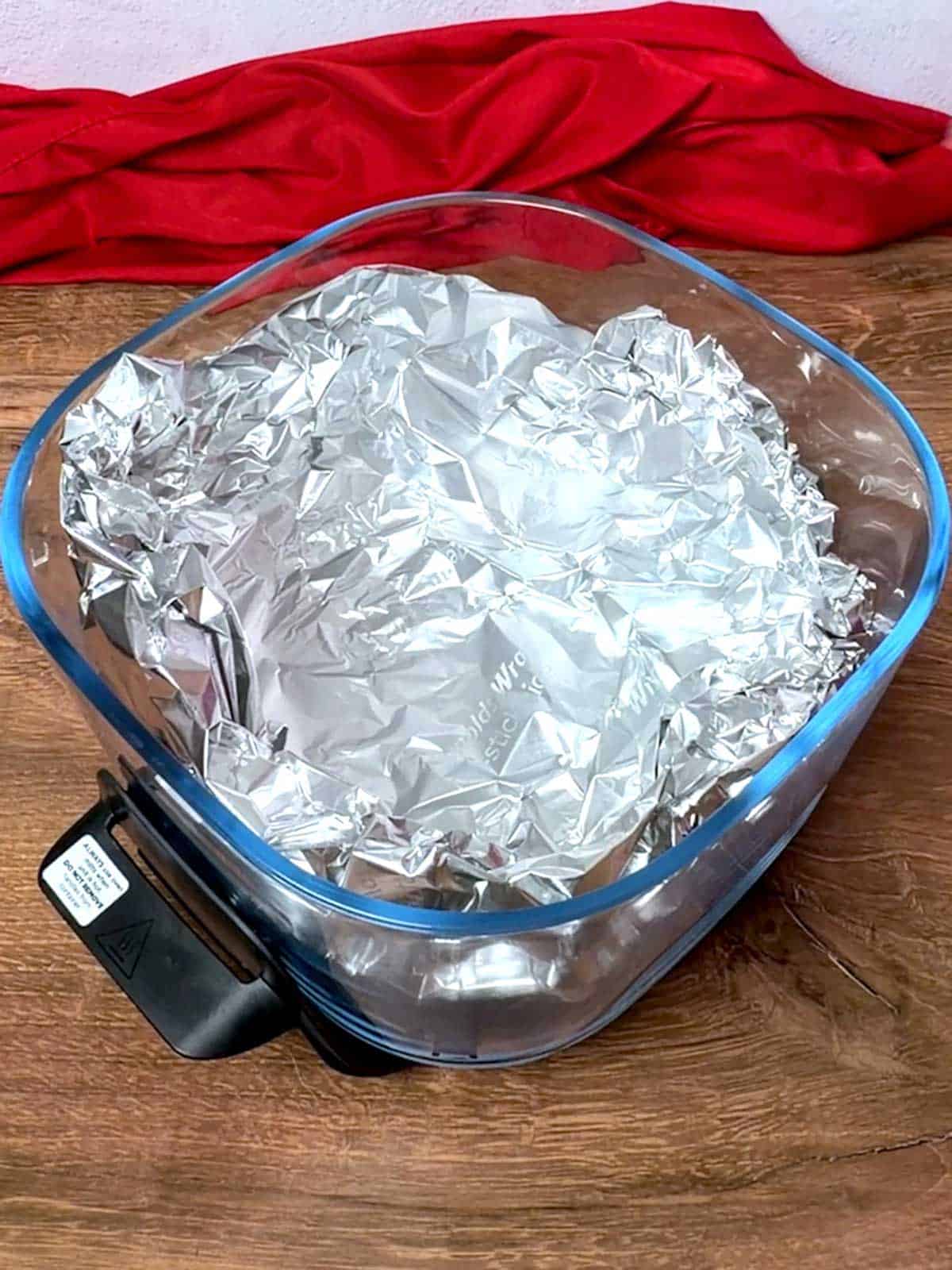 Bowl of the air fryer lined with aluminum foil.