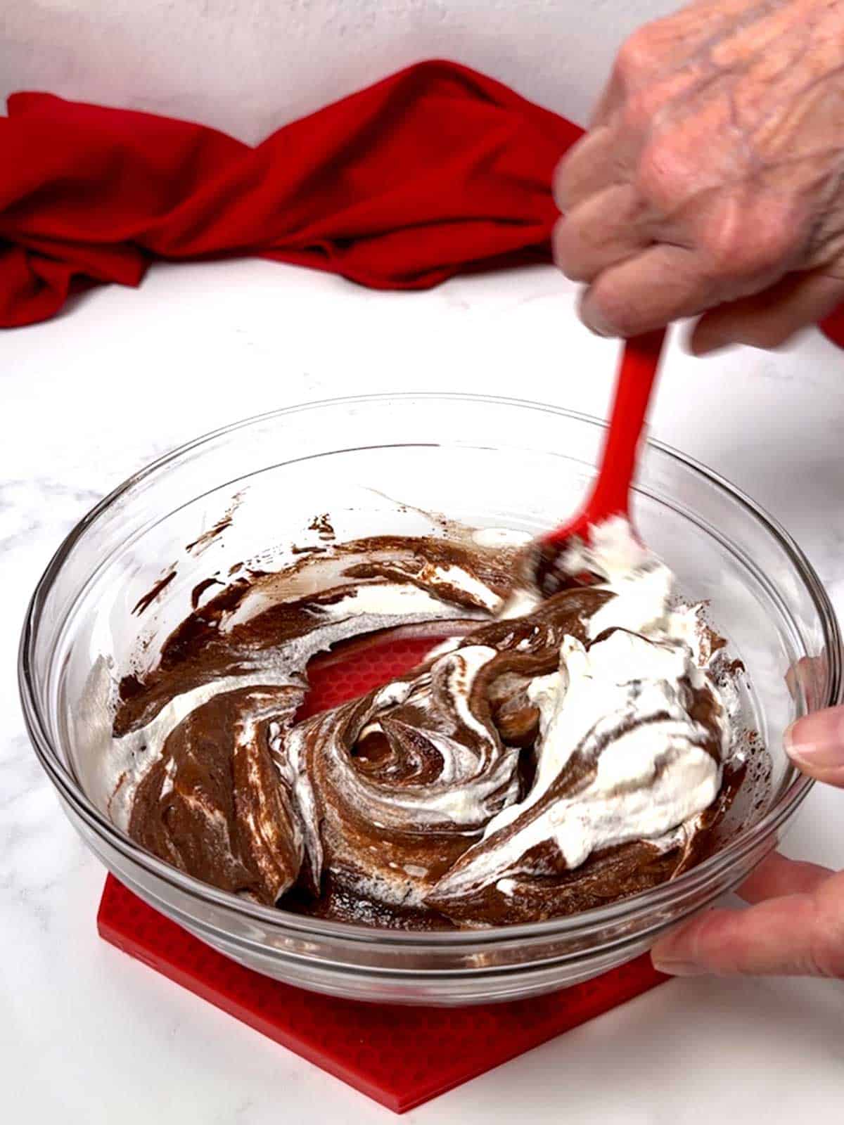 Folding whipped cream into the chocolate ganache.