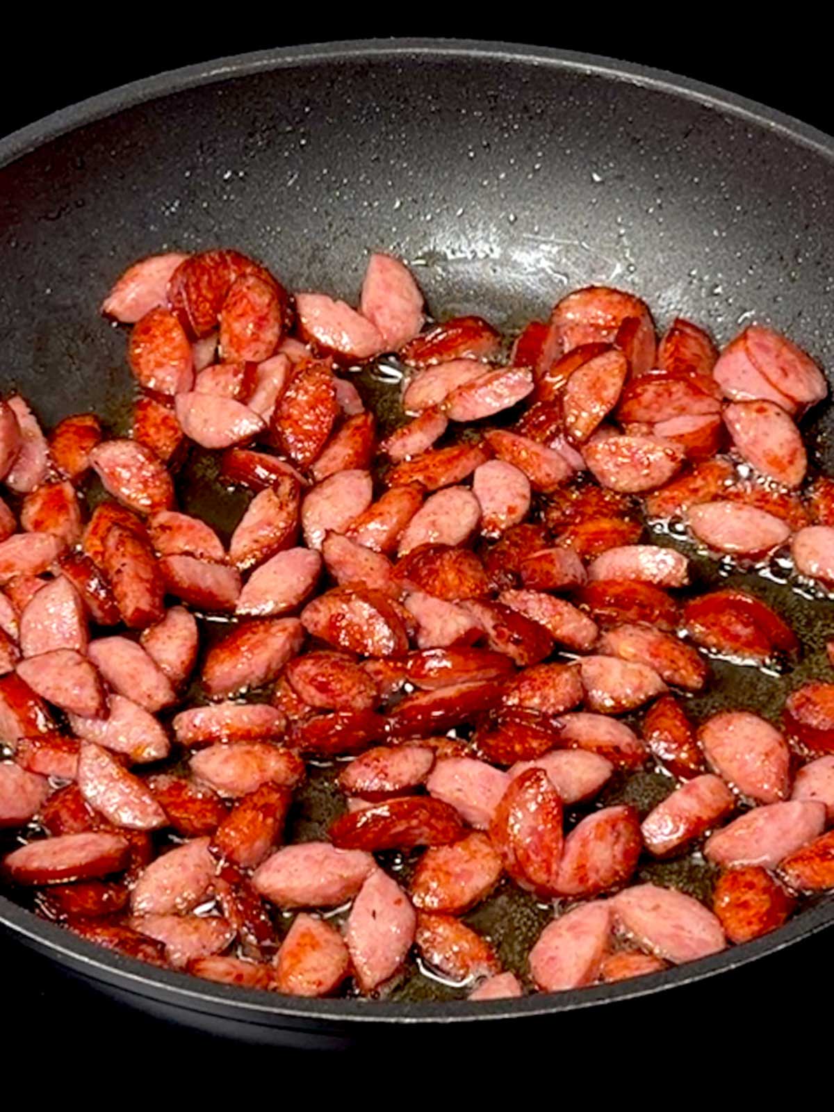Cooking the smoked sausage in a skillet.