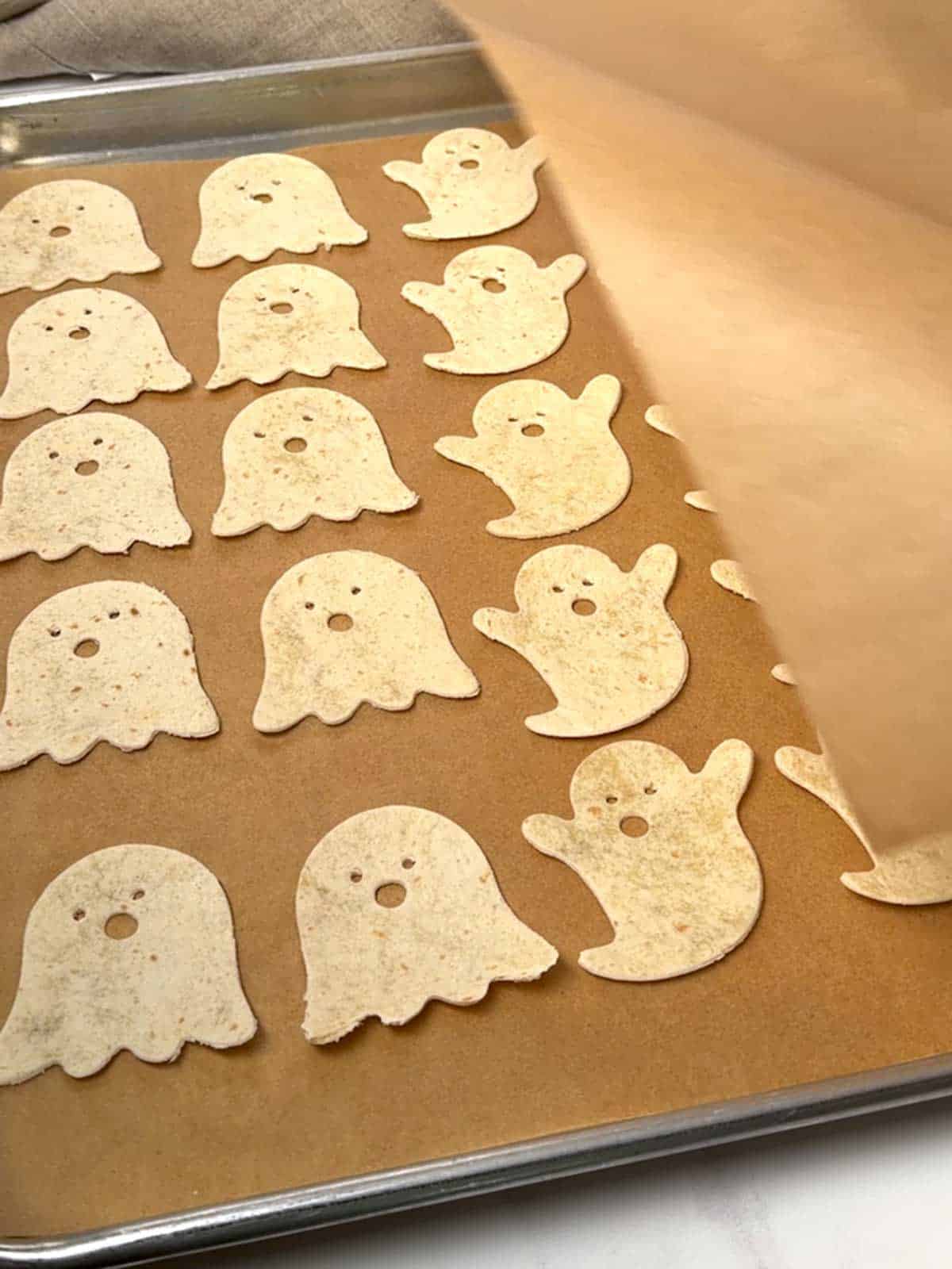 Covering ghost cutouts with parchment paper.