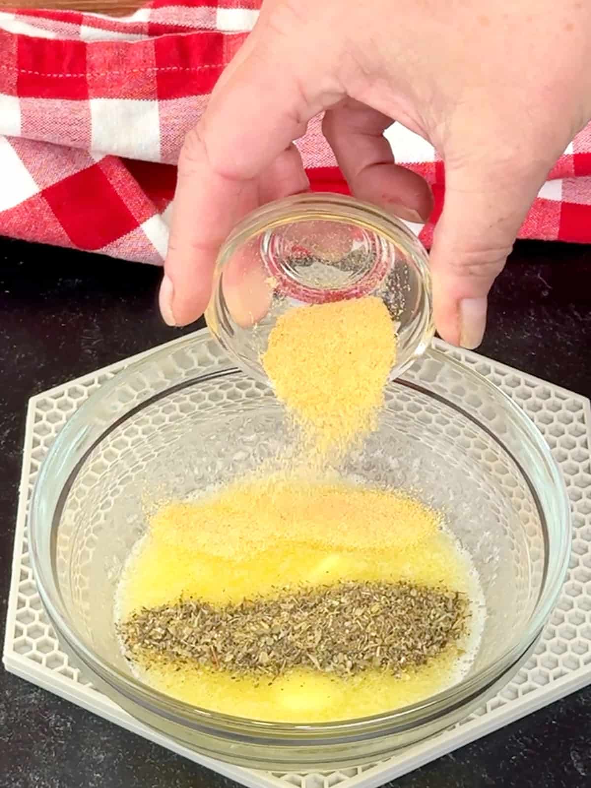 adding herbs and garlic to melted butter