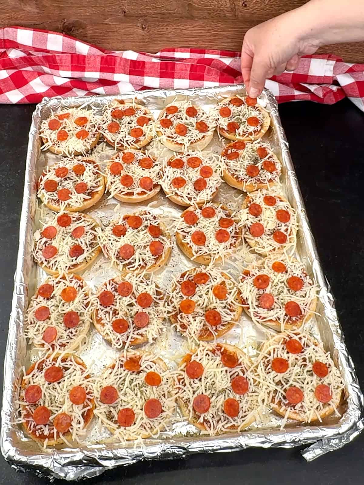 placing pepperoni on pizza bagels