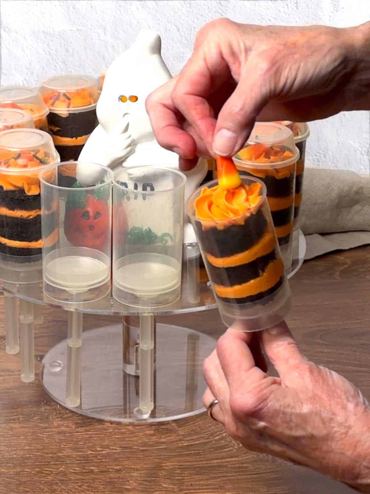Adding a piece of candy corn to the top of the push pop.

