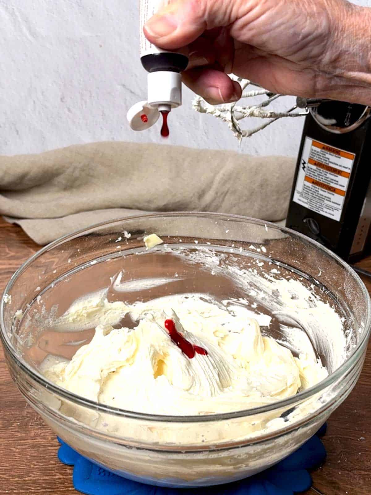 Adding orange gel food coloring to the frosting.
