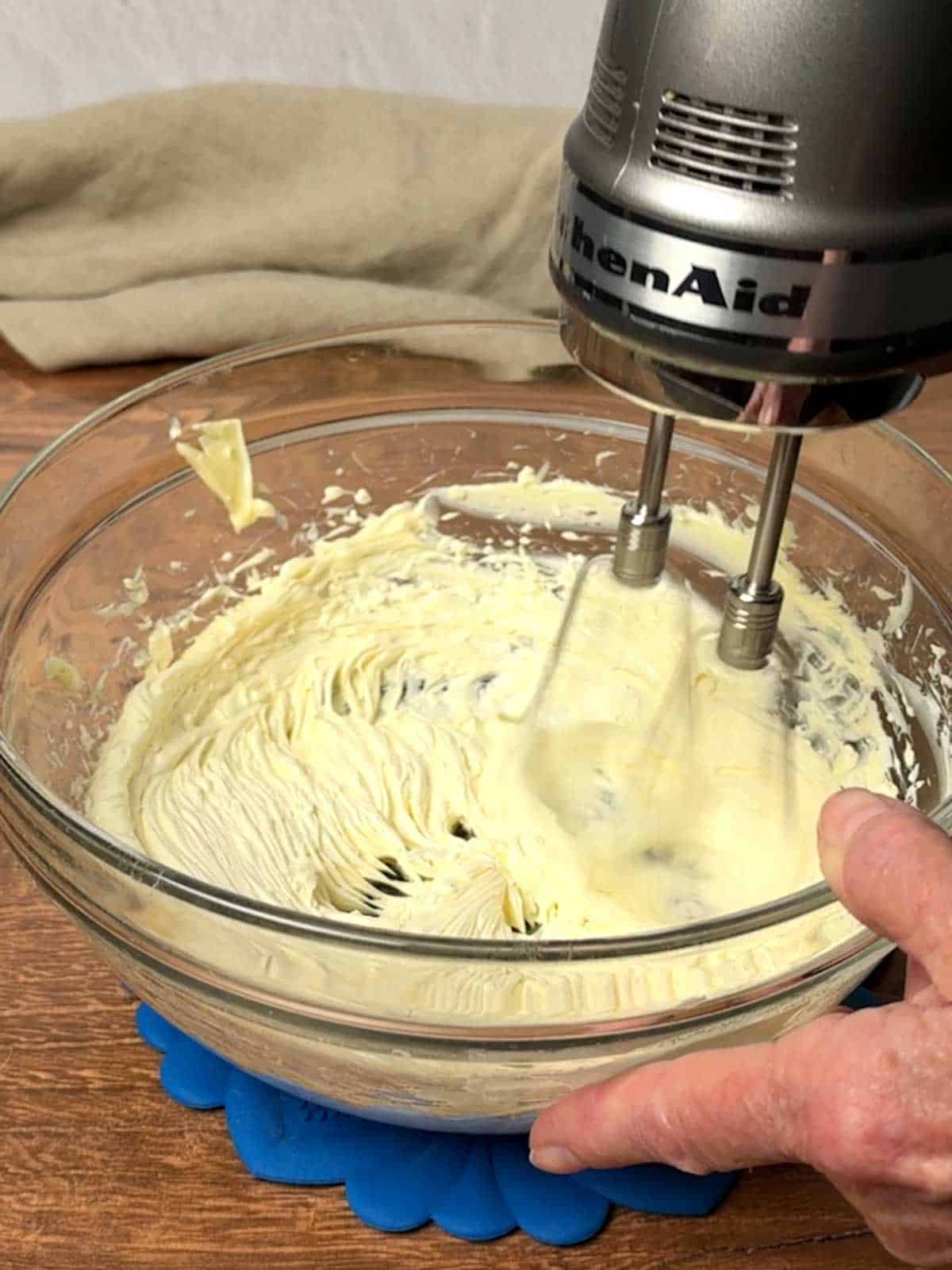 Beating butter and salt in a large bowl with electric mixer.